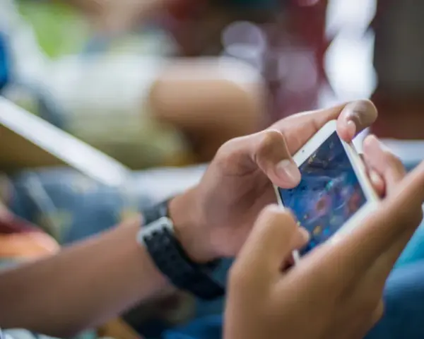 Ręce trzymające smartfon, grające w grę. Czy to przykład phubbing co to znaczy? Ignorowanie otoczenia dla telefonu.