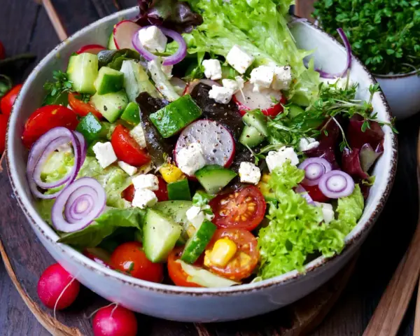 Ein bunter gemischter Salat mit Tomaten, Gurken, Radieschen, Zwiebeln und Feta.