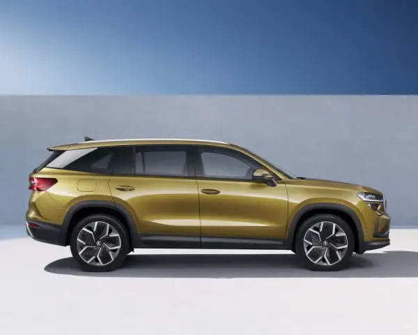 Złoty skoda suv z nowoczesnymi felgami stoi na tle niebieskiego nieba i szarej ściany.