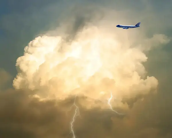 Samolot leci obok burzowej chmury z błyskawicami. To pokazuje, co to są turbulencje.