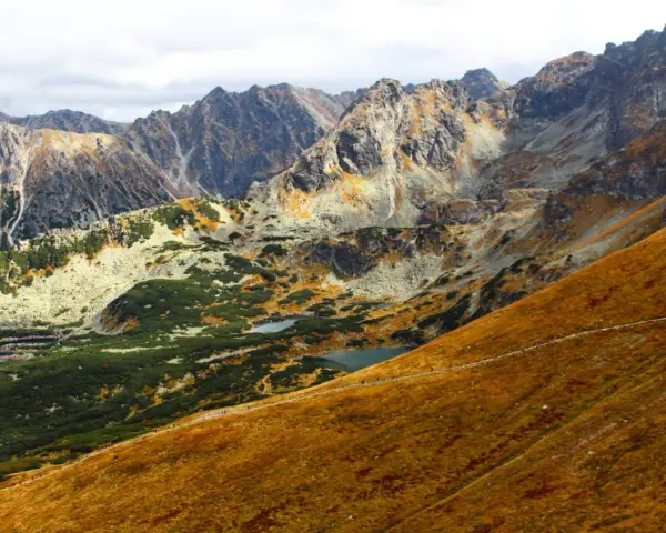 Widok na Tatry jesienią. Widać szlak turystyczny, którym idzie się na Kasprowy, małe stawy i skaliste szczyty.
