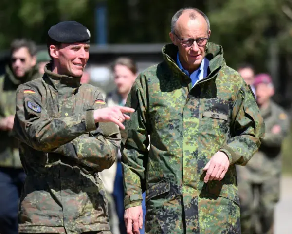 Dwóch mężczyzn w mundurach wojskowych, jeden z flagą Polski, drugi z napisem "MERZ" (Niemcy).