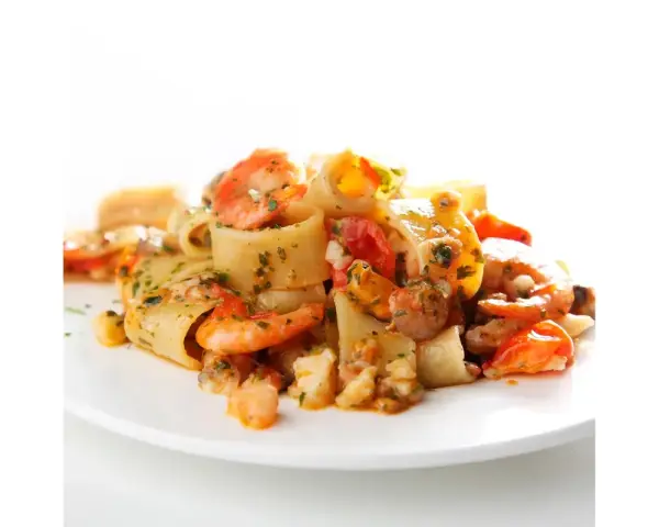 Piatto di calamarata allo scoglio con gamberi, cozze e pomodorini, condita con prezzemolo fresco.