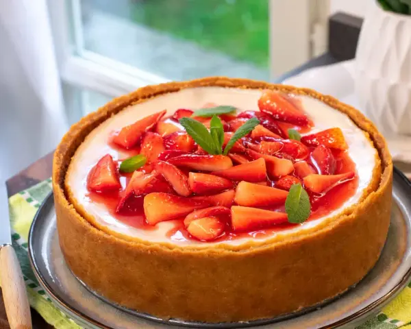 Cheesecake con mascarpone e fragole fresche, guarnita con menta. Un dolce invitante, perfetto per ogni occasione.