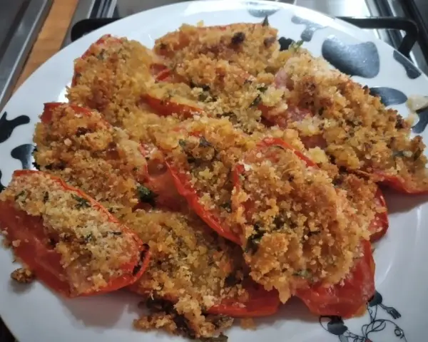 Pomodori gratinati al forno, un piatto semplice e gustoso, con una croccante panatura dorata e erbe aromatiche.