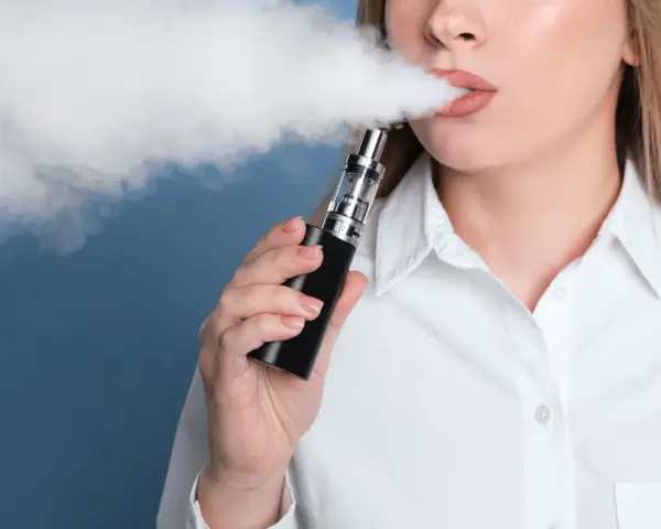 Mujer exhala vapor de un vaper, una alternativa moderna al tabaco tradicional.
