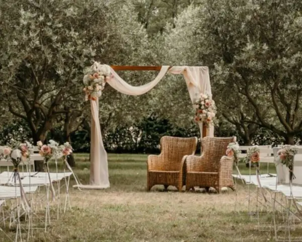 Un décor champêtre pour une célébration laïque : chaises blanches, arche fleurie, fauteuils en rotin sous les oliviers.