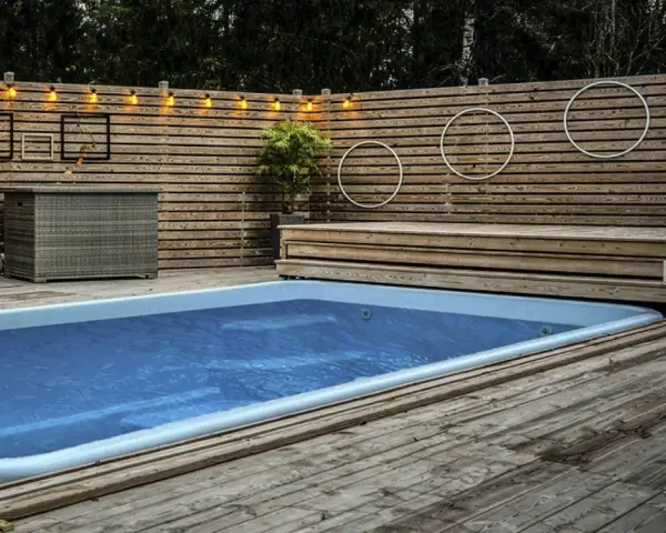 En avkopplande utomhusmiljö med pool och trädäck. En idé för att bygga eget pooltak kan inspireras av den snygga träpanelen och belysningen.