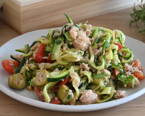 Deliziosa insalata di zucchine a spirale con tonno, pomodorini e olive verdi, un piatto fresco e leggero.