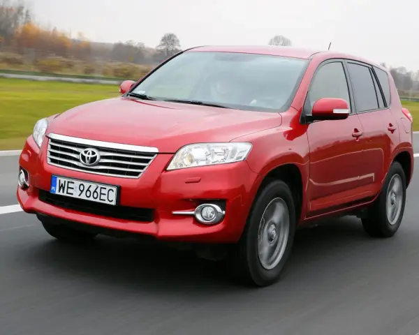 Czerwony SUV do 30 tys. na drodze, z widocznym grillem i tablicą rejestracyjną WE 966EC.