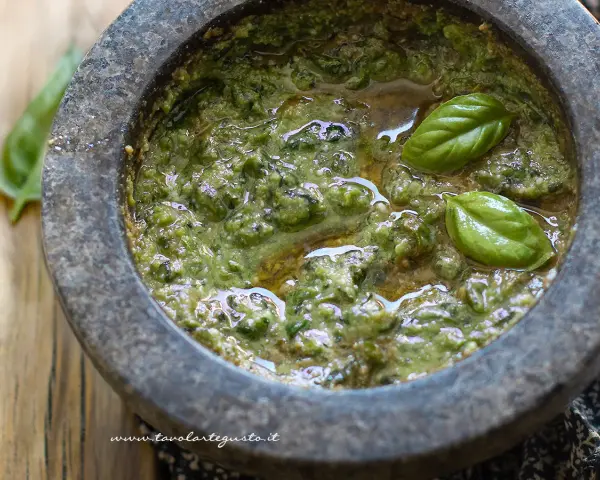 Pesto genovese originale appena preparato nel mortaio, con basilico fresco e olio d'oliva.