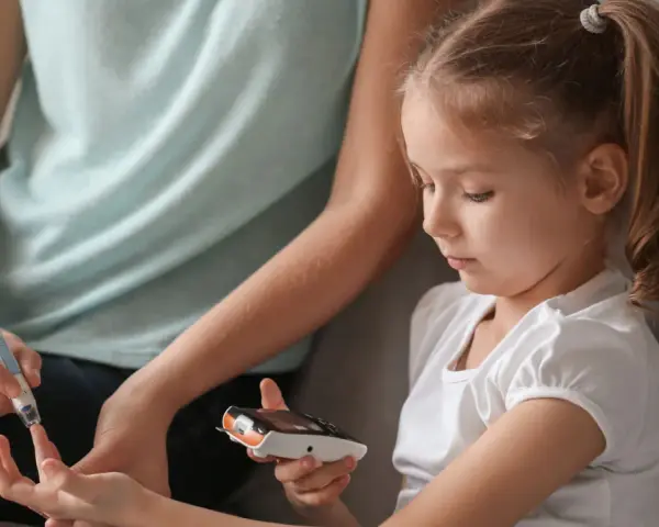 Mutter hilft Kind bei Blutzuckermessung. Ein wichtiger Teil im Leben mit diabetes kinder.