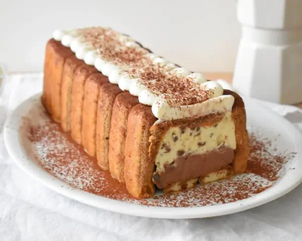 Pyszne włoskie ciasta: tiramisu w kształcie keksówki, otoczone biszkoptami, z kremem i kakao. Idealne na deser.