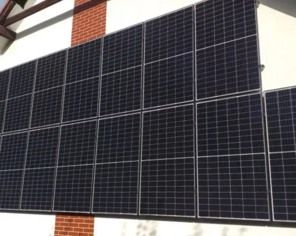 Duży zestaw paneli fotowoltaicznych na pionowej ścianie domu, zbierający energię słoneczną.