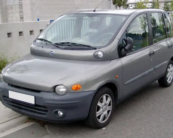 Szary Fiat Multipla, często uznawany za najbrzydsze auto na świecie, stoi na ulicy. Jego nietypowy kształt przyciąga wzrok.