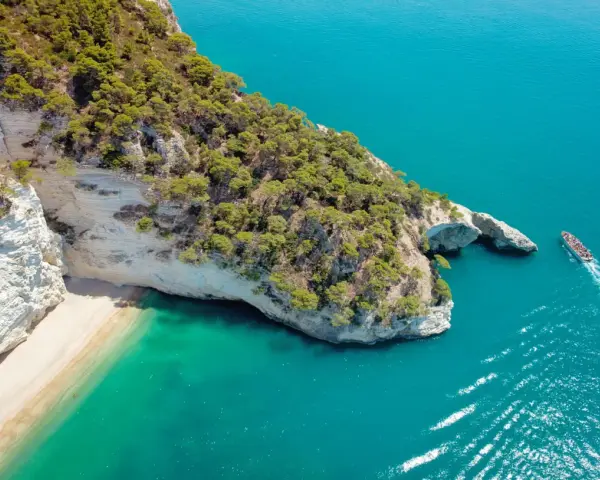 Widok z lotu ptaka na skaliste wybrzeże Włoch z plażą i turkusową wodą.