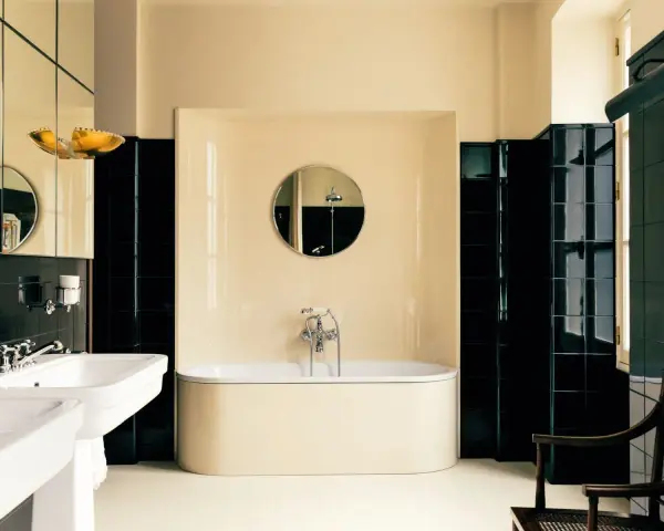 Élégante salle de bain noir et blanc avec baignoire îlot, lavabo double vasque et carrelage brillant.