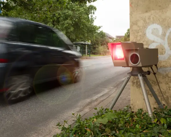 Ein Blitzer, der gerade ein Auto fotografiert, wie sehen Blitzer ohne Blitz aus? Dieses Gerät steht am Straßenrand, bereit für Geschwindigkeitsünder.