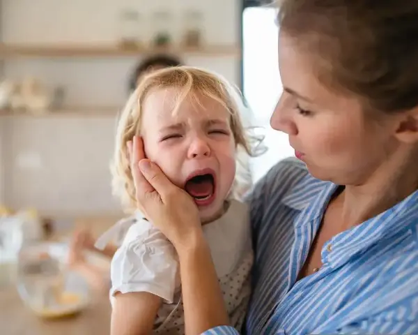 Mama próbuje uspokoić płaczące dziecko, które głośno krzyczy.