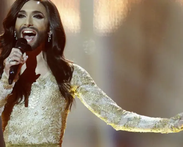 Conchita Wurst, zwyciężczyni Eurowizji, w złotej sukni z cekinami śpiewa na scenie.