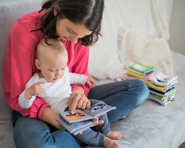 Mama czyta dziecku książeczkę o samochodach. Wycofane dziecko, przyczyny jego nieśmiałości mogą być różne, ale wspólne czytanie buduje więź.