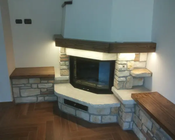 Un camino rustico in pietra e legno, con panche integrate. Un esempio di come costruire un camino rustico che unisce funzionalità ed estetica.