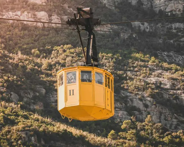 A yellow cable car ascends the rugged slopes of Montserrat.