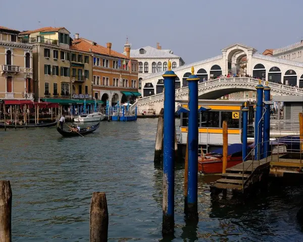 Venice canal with gondola, Rialto Bridge, and buildings.
