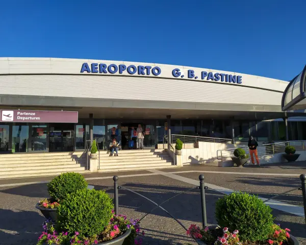 Wejście do Aeroportu G.B. Pastine w Rzymie Ciampino. Słoneczny dzień, ludzie czekają na odloty.