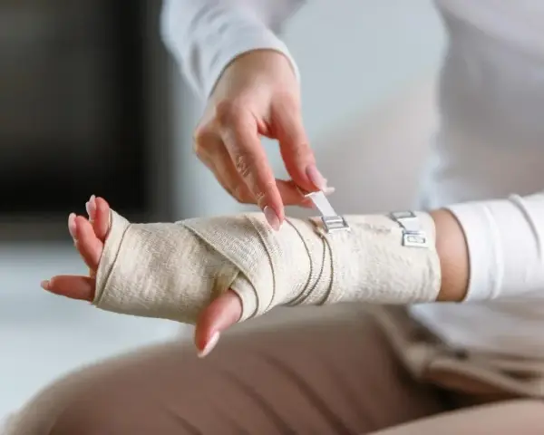 Dłoń owinięta bandażem, zapięcie na rzepy. Prezentacja bandażowania po urazie.