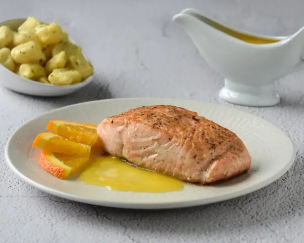 Filete de salmón a la naranja, servido con gajos de naranja y una salsa dorada. Acompañado de patatas pequeñas.