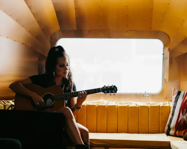 Sarah Jones, piosenkarka, gra na gitarze w przytulnym wnętrzu.