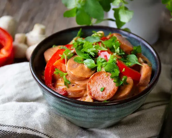 En mustig korvgryta med chorizo, paprika och örter i en krämig sås. Serveras i en rustik skål.