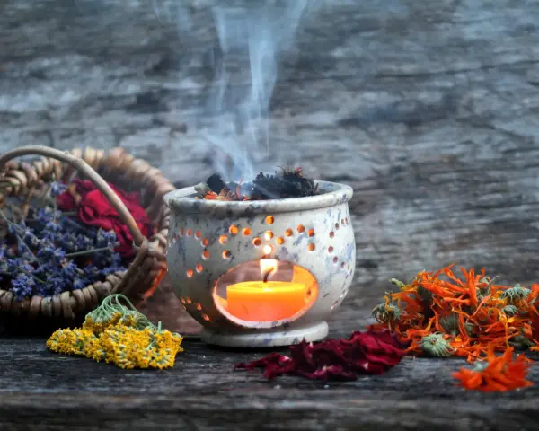Aromas de lavanda, rosas y caléndula se elevan con el humo de un quemador de incienso, creando un ambiente de limpieza de energías.