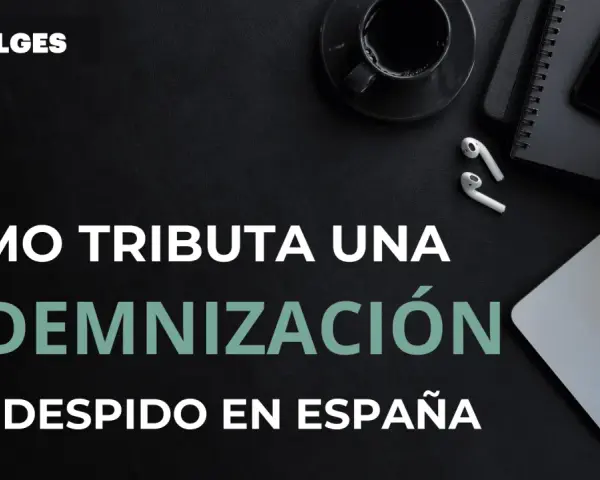 Cómo tributa una indemnización por despido improcedente en España. Imagen de escritorio con portátil, móvil y café.