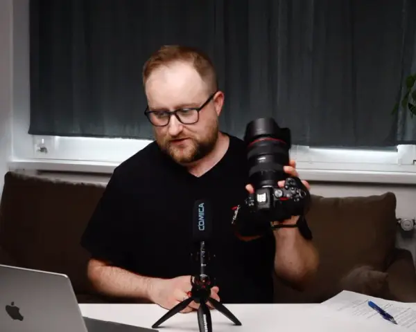Mężczyzna prezentuje aparat fotograficzny, omawiając elementy kursu fotografii dla początkujących.