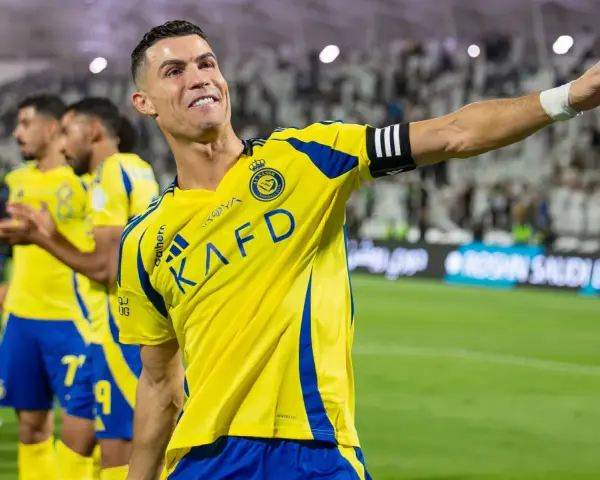 Uśmiechnięty Cristiano Ronaldo w żółtej koszulce Al Nassr, świętujący sukces. Jego zarobki w Arabii Saudyjskiej budzą podziw.
