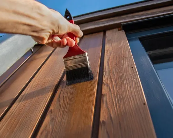 Application d'une couche protectrice sur des lattes de bois avec une peinture à l'huile sur bois technique.