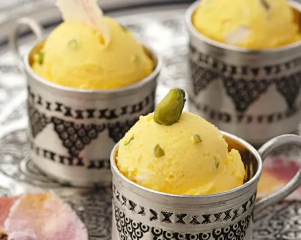 Gelbes Eis mit Pistazien in silbernen Bechern. Die süße Glucose-Verwendung sorgt für die cremige Konsistenz.