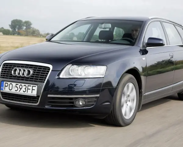 Ciemnogranatowe Audi A6 C6 3.2 FSI Avant w ruchu. Kierowca za kierownicą. Wady tego modelu mogą dotyczyć np. układu napędowego.