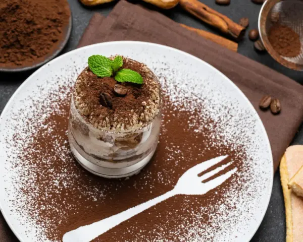 Pyszne tiramisu w pucharku, posypane kakao i kawą. Idealne desery co zamiast surowych jaj, z miętą i biszkoptami.