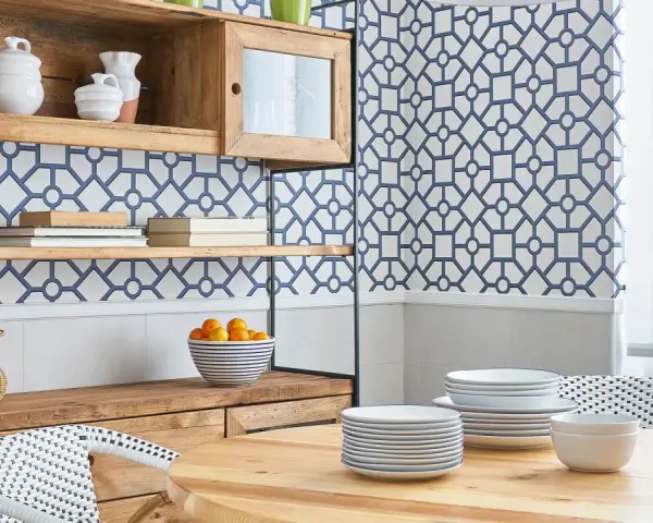 Cocinas con papel pintado azul y blanco, estanterías de madera, vajilla y una mesa de comedor.