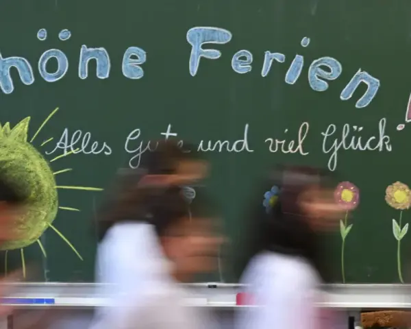 Kreidetafel mit "Schöne Ferien" und einem lachenden Smiley, bereit für die herbstferien 2025 nrw. Kinder huschen vorbei.