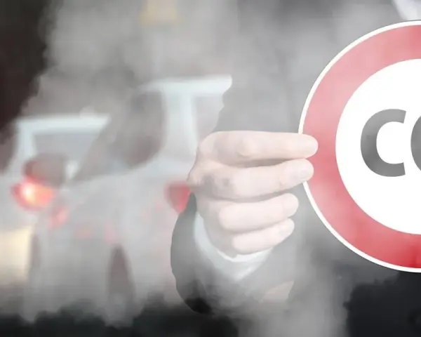 Ręka trzyma znak z napisem CO2 na tle korka ulicznego. Symbolizuje to potrzebę ograniczenia emisji, jak w przypadku certyfikatu CE dla produktów.