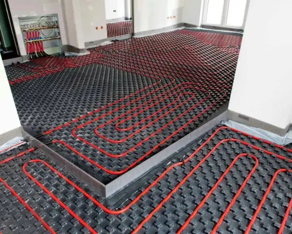 Instalación de un sistema de calefacción por suelo radiante, con tuberías rojas serpenteando sobre una base negra. Preparando un suelo refrescante para el confort.