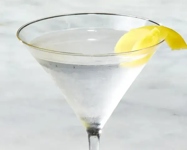 Chłodny martini z ginem, ozdobiony skórką cytryny, czeka na degustację.