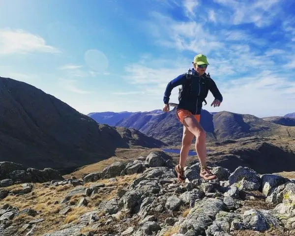 Atleta corre su sentiero roccioso in montagna. Il fast hiking significato è correre in montagna con attrezzatura leggera.