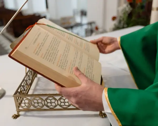 Kapłan w zielonej szacie czyta księgę podczas mszy żałobnej.