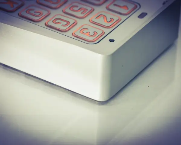 Zbliżenie na klawiaturę domofonu z podświetlanymi na pomarańczowo przyciskami z cyframi.