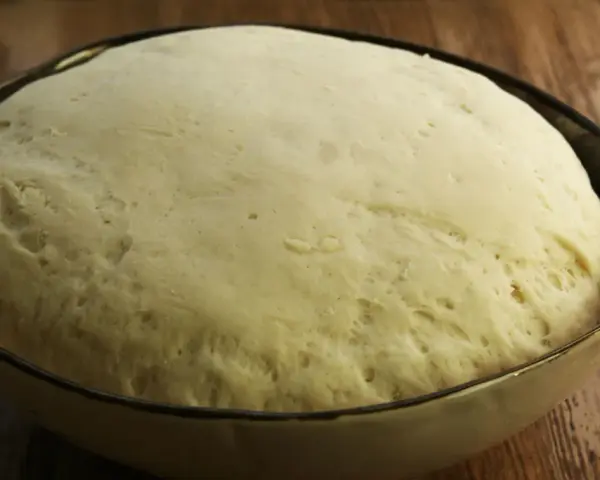 Wyrośnięte ciasto na pizzę w misce, gotowe do dalszej obróbki. Idealny przepis na ciasto do pizzy czeka!